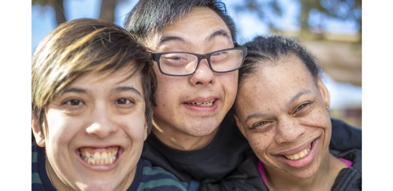 Three people's faces smiling at the camera